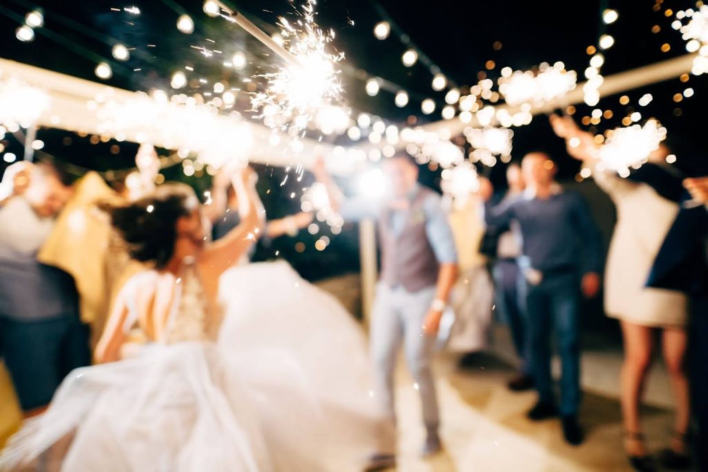 Foto borrosa y estética de una pareja bailando con bengalas en su boda
