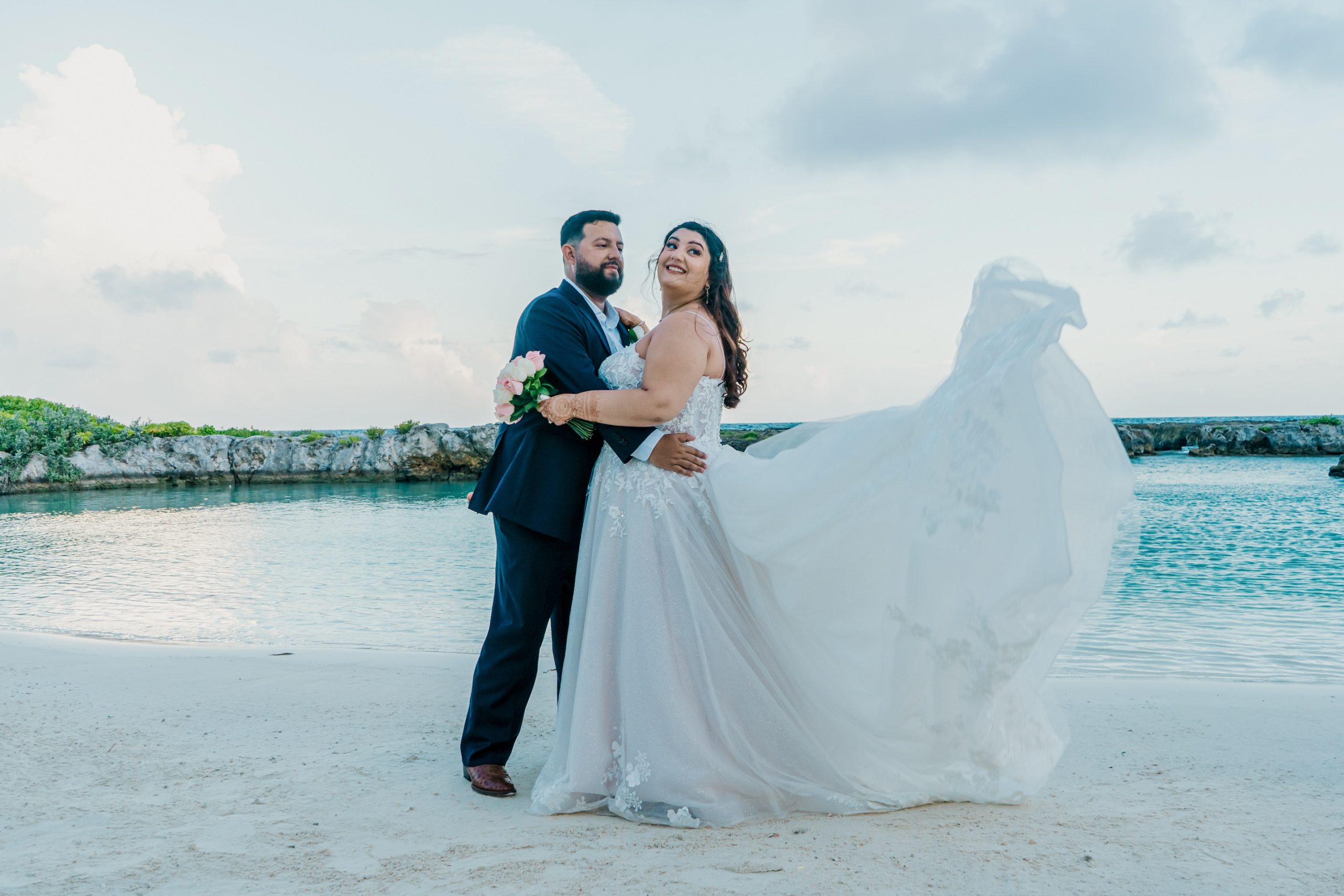 Bride and Groom pose in front of Hard Rock Hotel Riviera Maya Bay